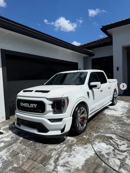 A white Shelby F-150 covered in foam-cannon suds on a paver driveway