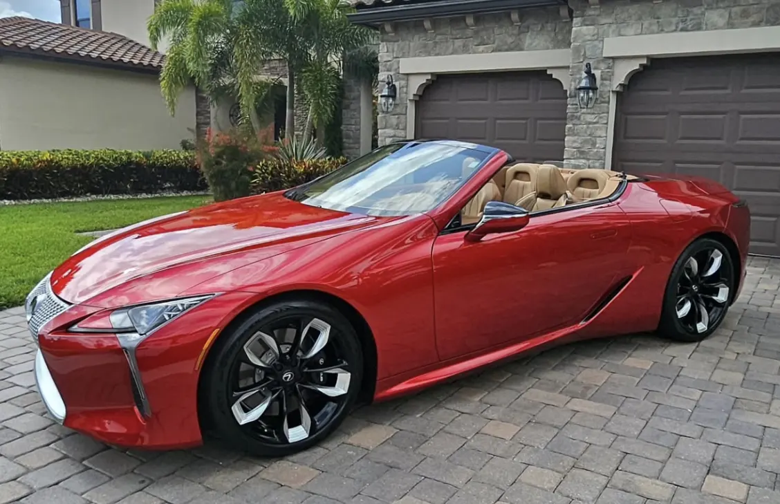 A red Lexus convertible with the top down, detailed in the driveway